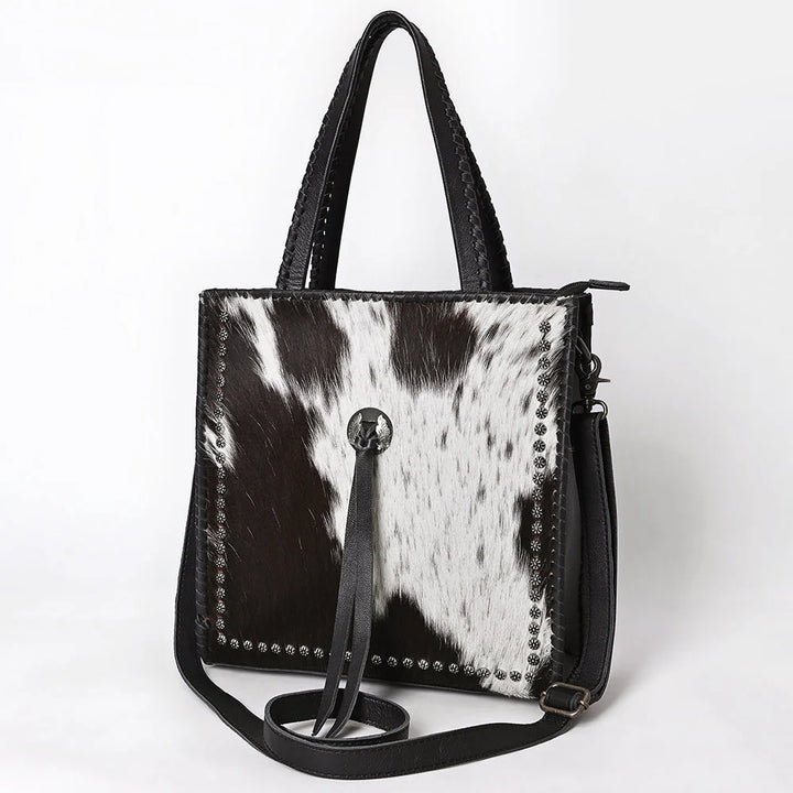 Side angle of American Darling cowhide tote featuring genuine leather details and fringe accents.